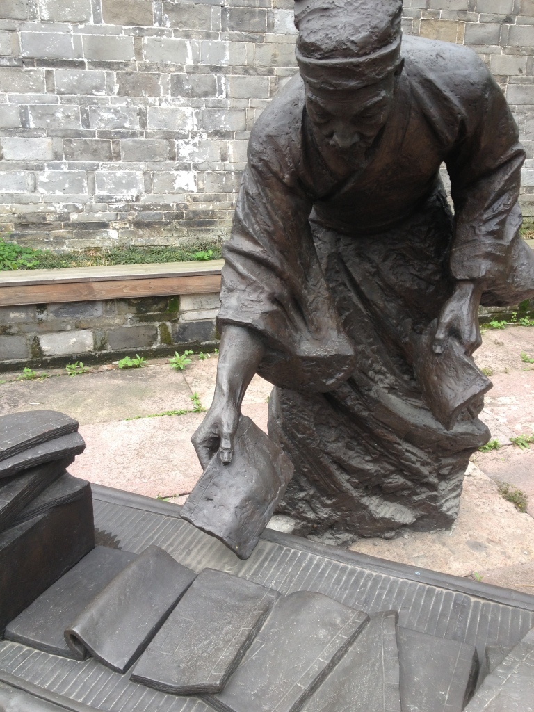 A statue depicting the process of collecting written works
